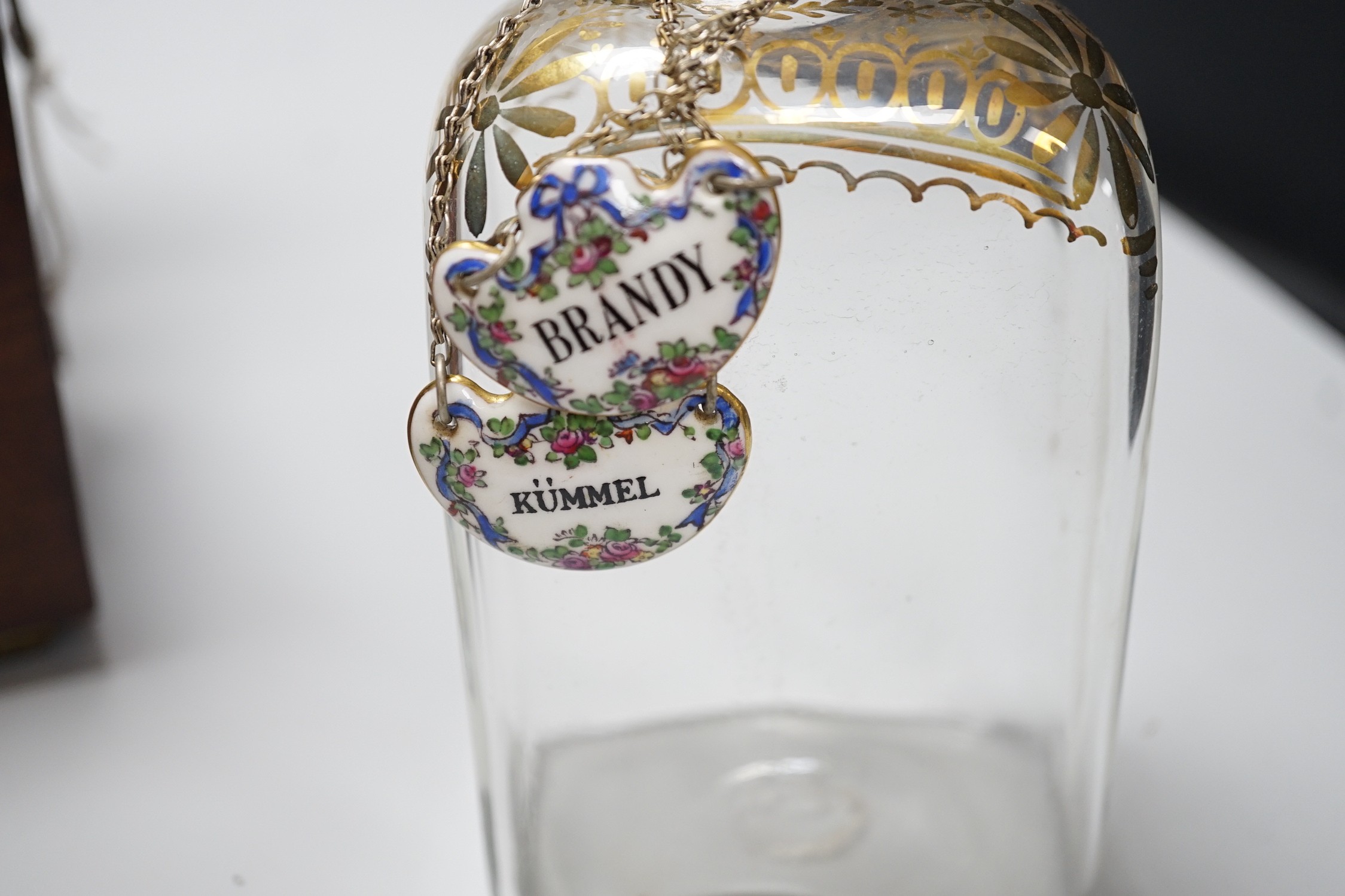 A George III inlaid mahogany decanter set with four gilt decorated decanters and two T.Goode & Co. enamelled wine labels, ‘BRANDY’ and ‘KÜMMEL’. 21cm tall
